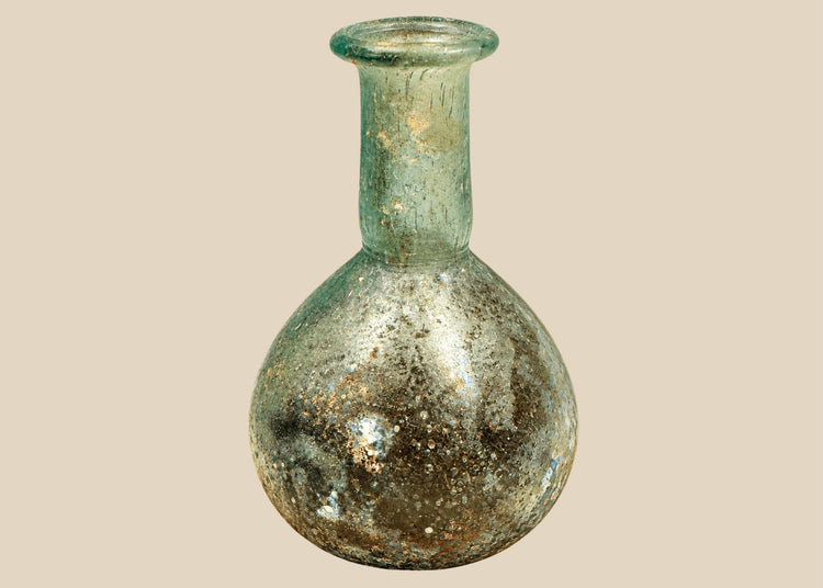 Ancient Roman pale green glass unguentarium, circa 1st–2nd century CE, featuring a globular body, elongated neck, and outward-flaring folded rim.