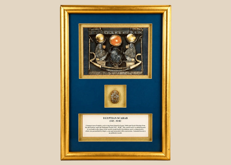 Framed ancient Egyptian scarab amulet dating to circa 2345–30 BCE, featuring blue-green glazing and decorative gold-toned presentation.