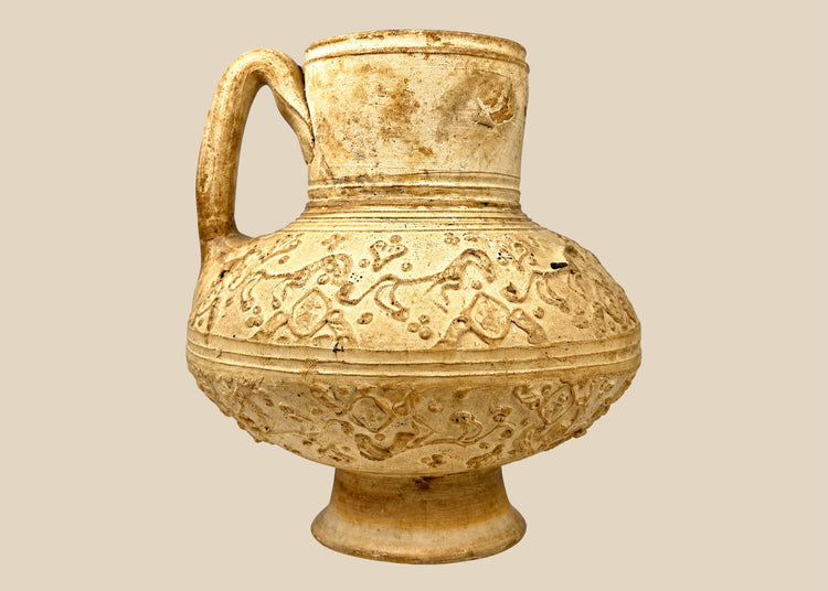 Medieval Persian Seljuk-style pottery ewer dating to the 12th–13th century, featuring raised animal relief decoration and a curved handle.