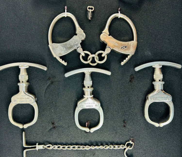 Close-up of engraved THE IRON CLAW 50464 T-bar handcuffs with open-jaw links and small key
