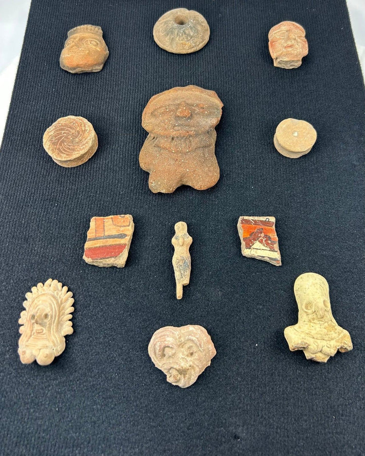 Ancient terracotta heads and figurines from Mesoamerica showcased in a black frame