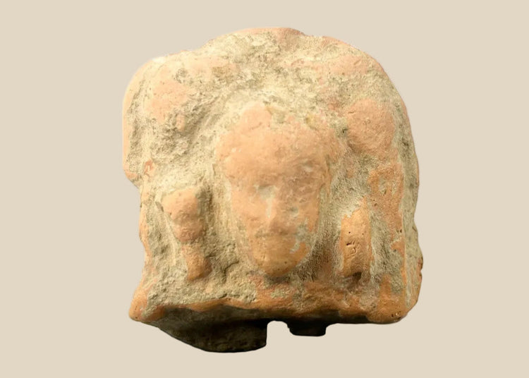 Ancient Gandharan terracotta plaque fragment with central male bust and faint side figures, reddish-brown surface, mounted on black display base, photographed on a white background.
