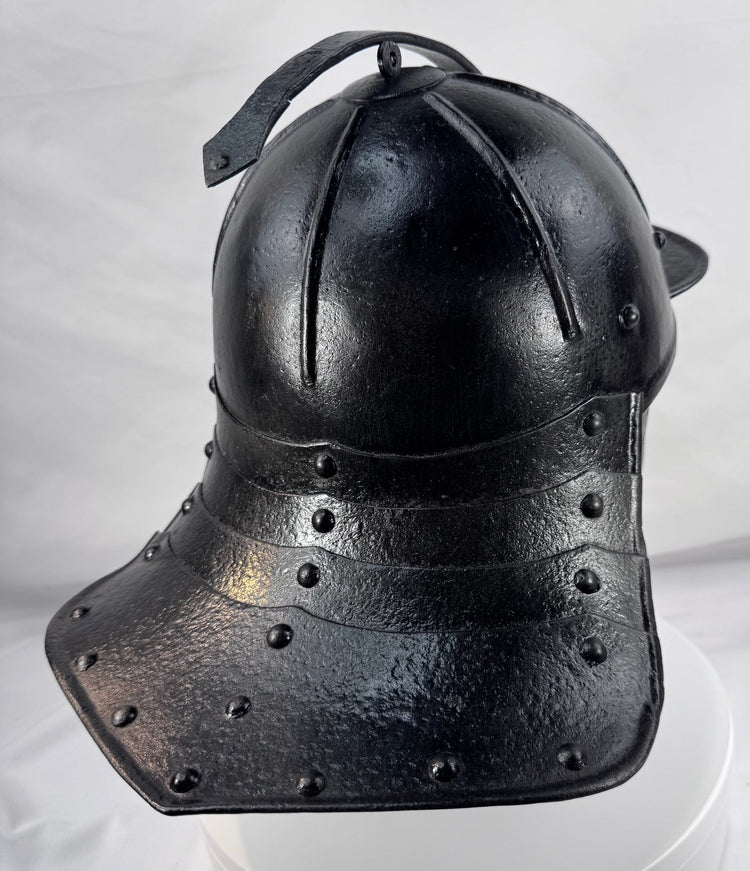 Rare Northern European forged iron combat helmet featuring rolled borders, ring finial, and articulated neck defense.