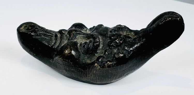 Antique cast metal oil lamp in the form of a satyr head with filling aperture and wick nozzle.