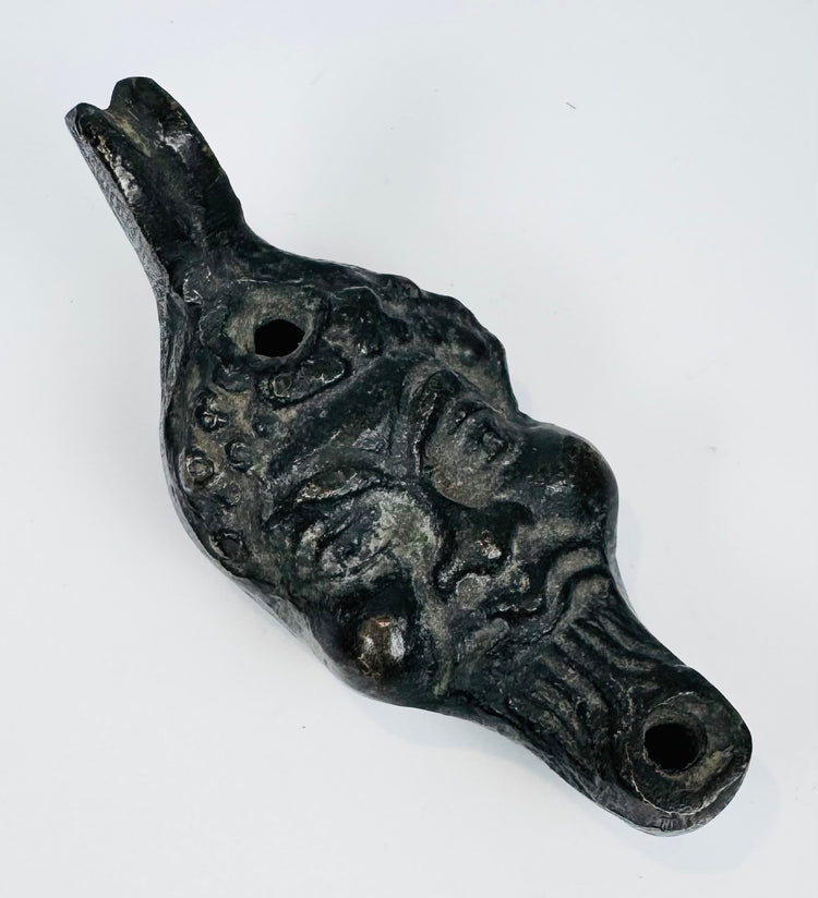 European figural oil lamp depicting a stylized satyr mask with pronounced facial features and beard.