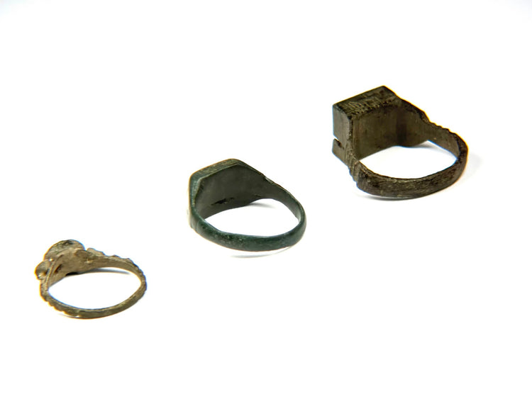 Three Late Roman to Early Byzantine bronze finger rings shown from rear and side angles, including square signet and oval bezel forms, circa 3rd–7th century CE
