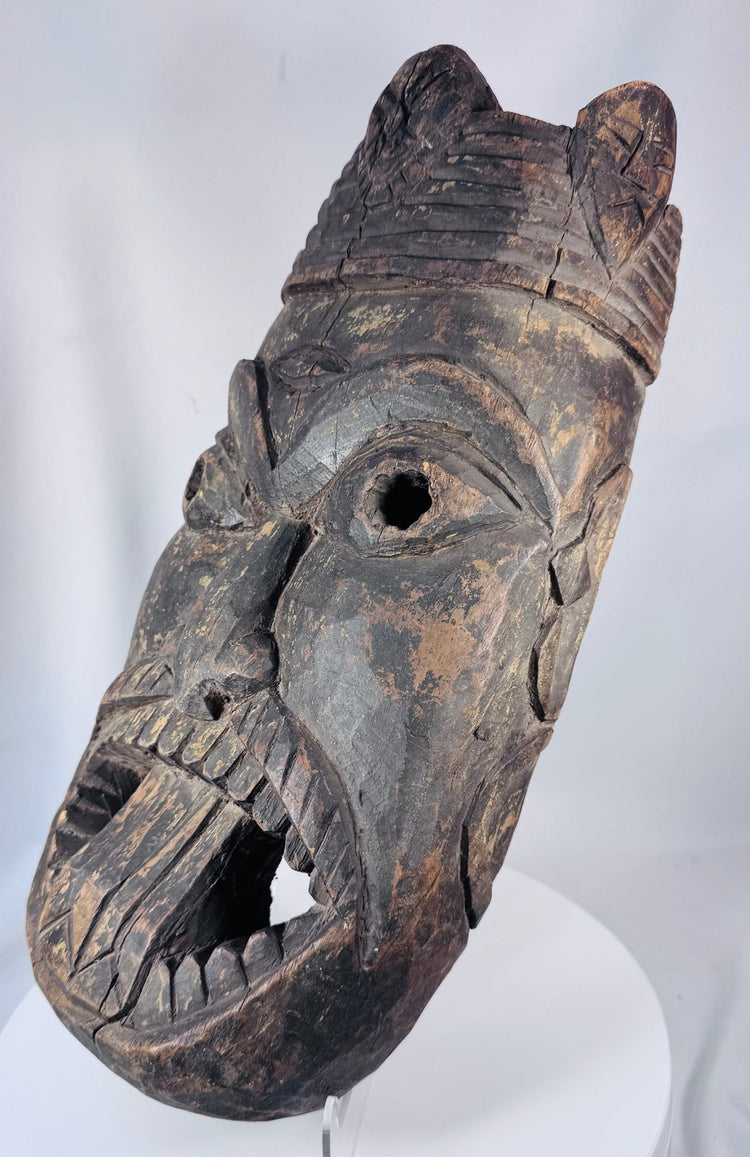 Hand-carved West African spirit mask with expressive facial expression and ceremonial sculptural form.