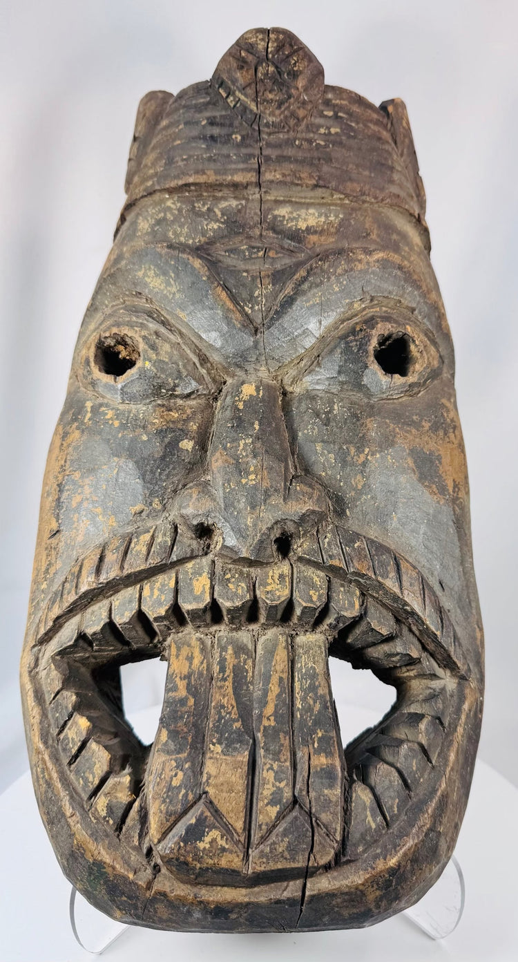 Hand-carved West African wooden ritual mask featuring recessed eyes, carved teeth, and aged patina.