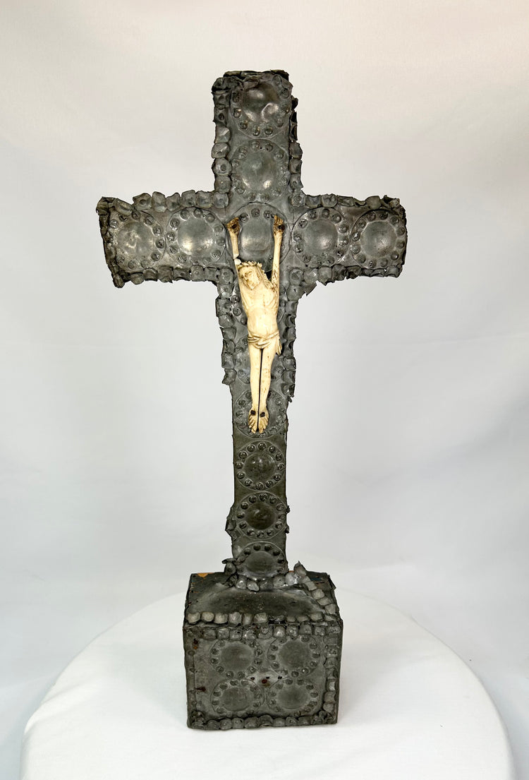 Antique hand-carved crucifix featuring a bone corpus on a repoussé-decorated wooden cross with aged patina, displayed on a white background.