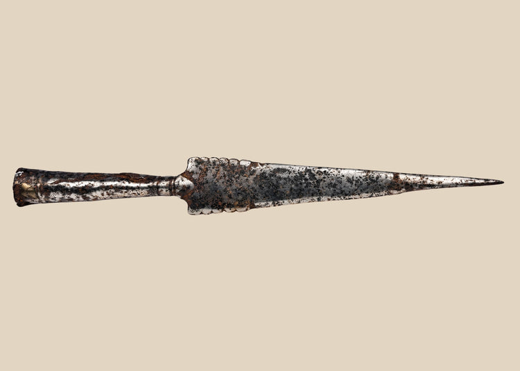 Forged iron spearhead from Europe, Iron Age to Early Medieval period (circa 1st millennium CE), featuring a scalloped-edge blade, socketed base, and historic mixed-metal brazed repair. Natural patina and surface texture reflect centuries of use, craftsmanship, and cultural significance as both a functional weapon and symbol of status.
