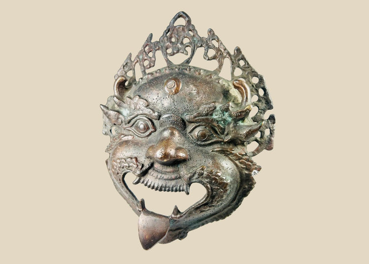 Late 19th–early 20th century Himalayan bronze or brass ritual mask, depicting fierce protective deity with wide eyes and grimacing mouth, traces of pigment, patina, used in Buddhist or Hindu ceremonies