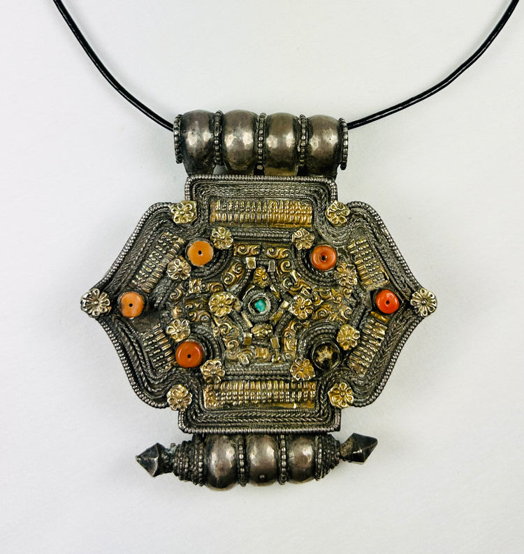 Hexagonal Himalayan gau (ghau) amulet pendant in silver-tone alloy with parcel-gilt filigree, rosette appliqués, inset coral beads, and small turquoise cabochon, featuring hollow reliquary cavity and tubular suspension bales, late 19th–early 20th century, Tibet/Nepal