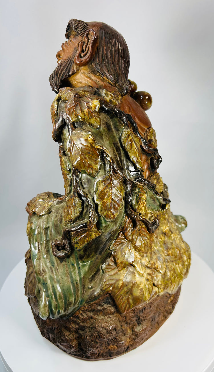 Chinese ceramic figure of Jigong the Mad Monk seated on rocky base with mottled glaze.
