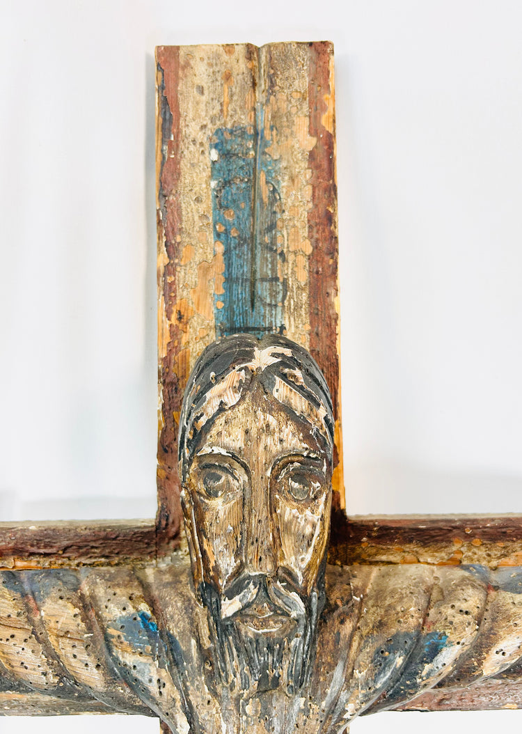 Spanish Colonial Christ on cross sculpture with aged surface and polychrome traces.