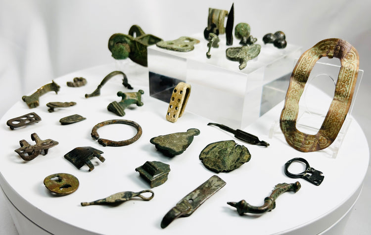 Ancient Roman bronze artifact collection featuring belt fittings, decorative appliqués, harness mounts, and a small spearhead from the Roman Imperial period
