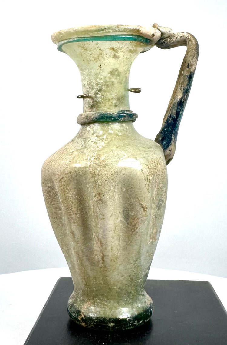 Eastern Mediterranean glass jug featuring decorative blue-green trailing beneath the mouth and a raised glass band encircling the lower neck.