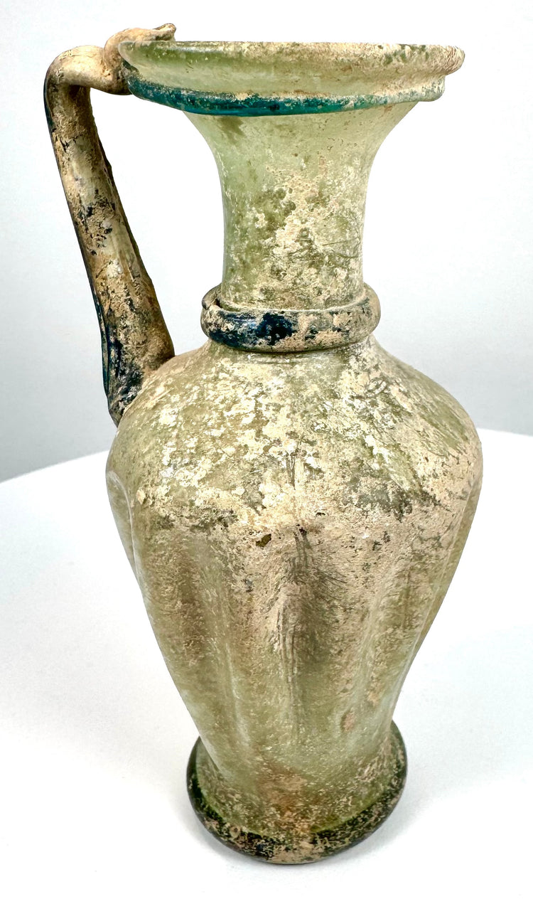 Roman–Byzantine glass vessel featuring a rounded, slightly flared base, elegant ovoid body, and weathered glass surfaces.