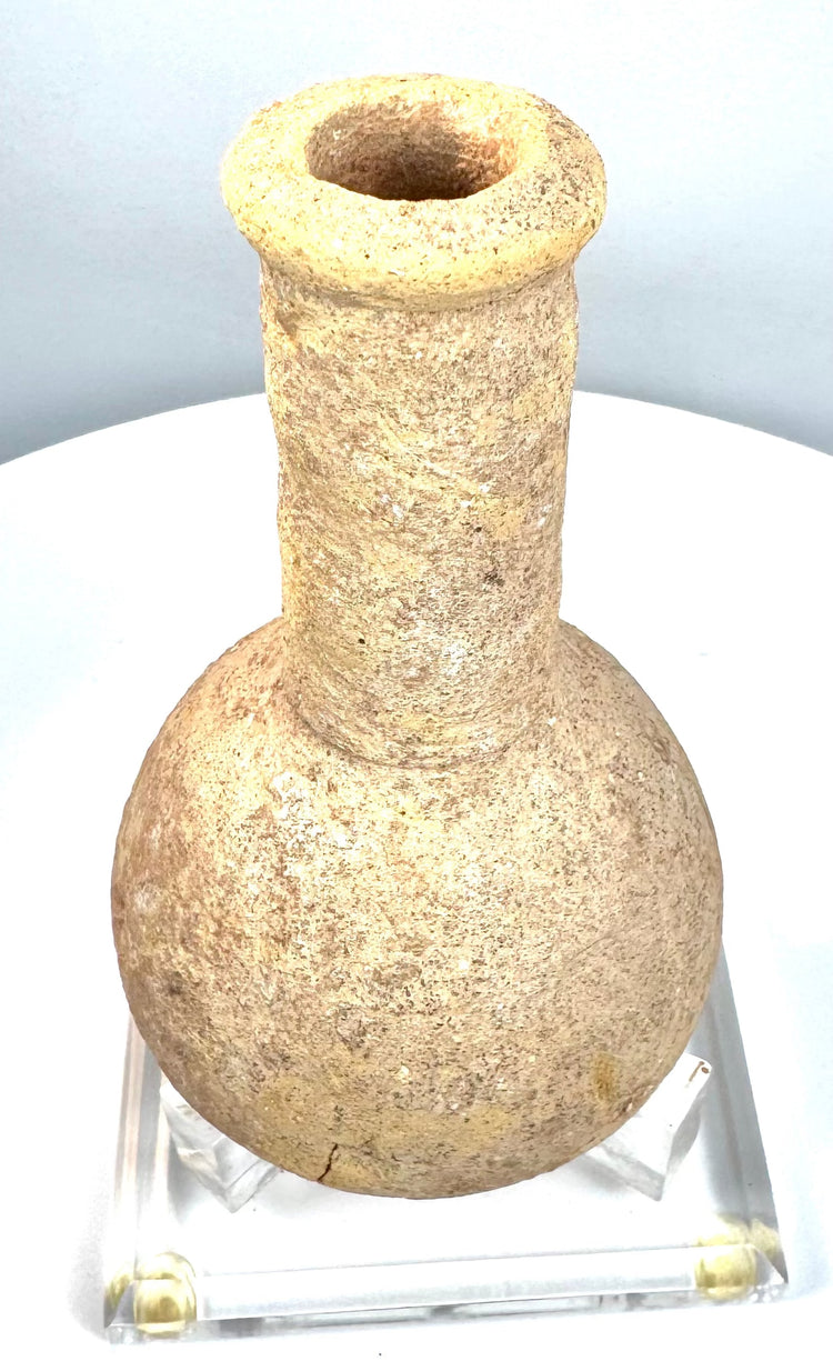 Ancient Roman carved stone unguentarium displaying a thick outward-flaring rim, circular mouth, and distinctive porous stone construction.