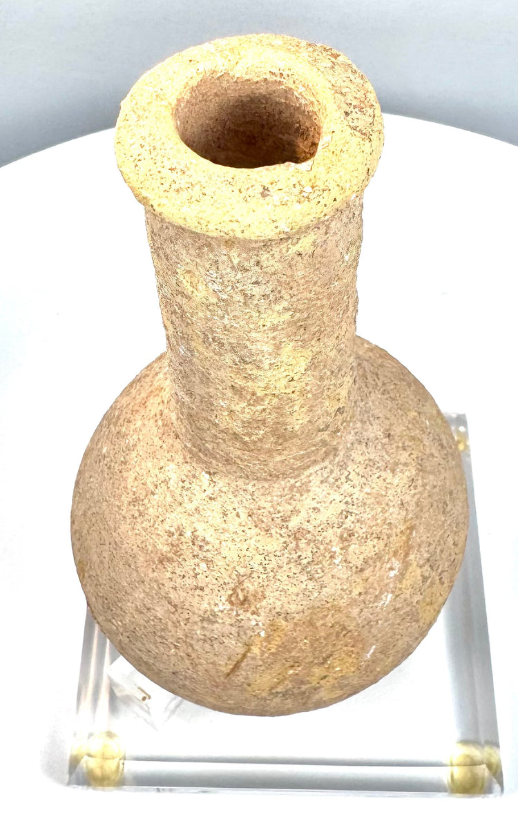 Ancient Roman Imperial unguentarium with a long cylindrical neck, pronounced rounded shoulders, and coarse granular stone texture.