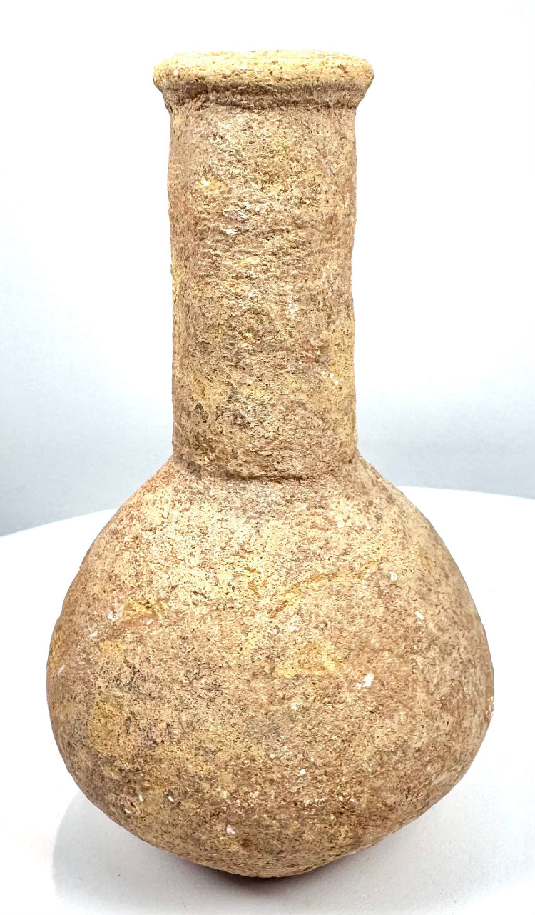 Roman stone unguentarium attributed to the 1st–3rd century CE, featuring a globular body, cylindrical neck, thick rim, and archaeological surface deposits.
