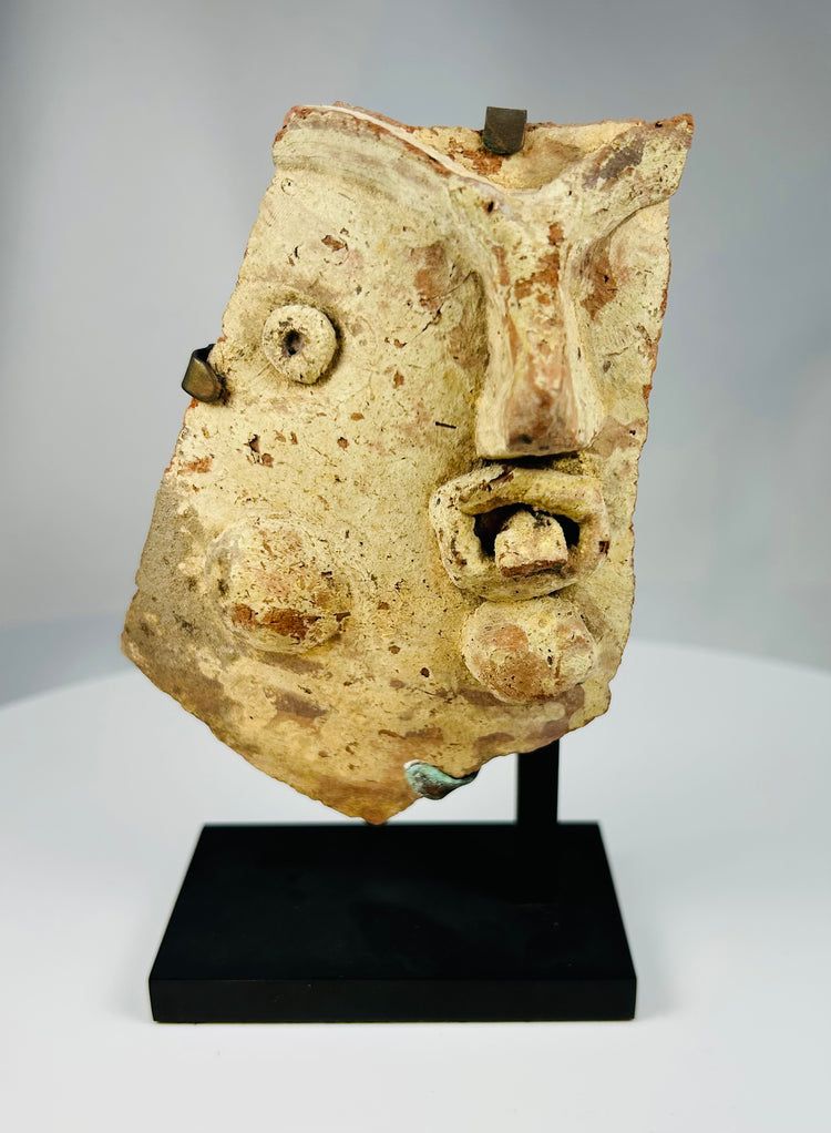 Classical Mediterranean terracotta theater mask fragment with expressive features from the Hellenistic-Roman era.