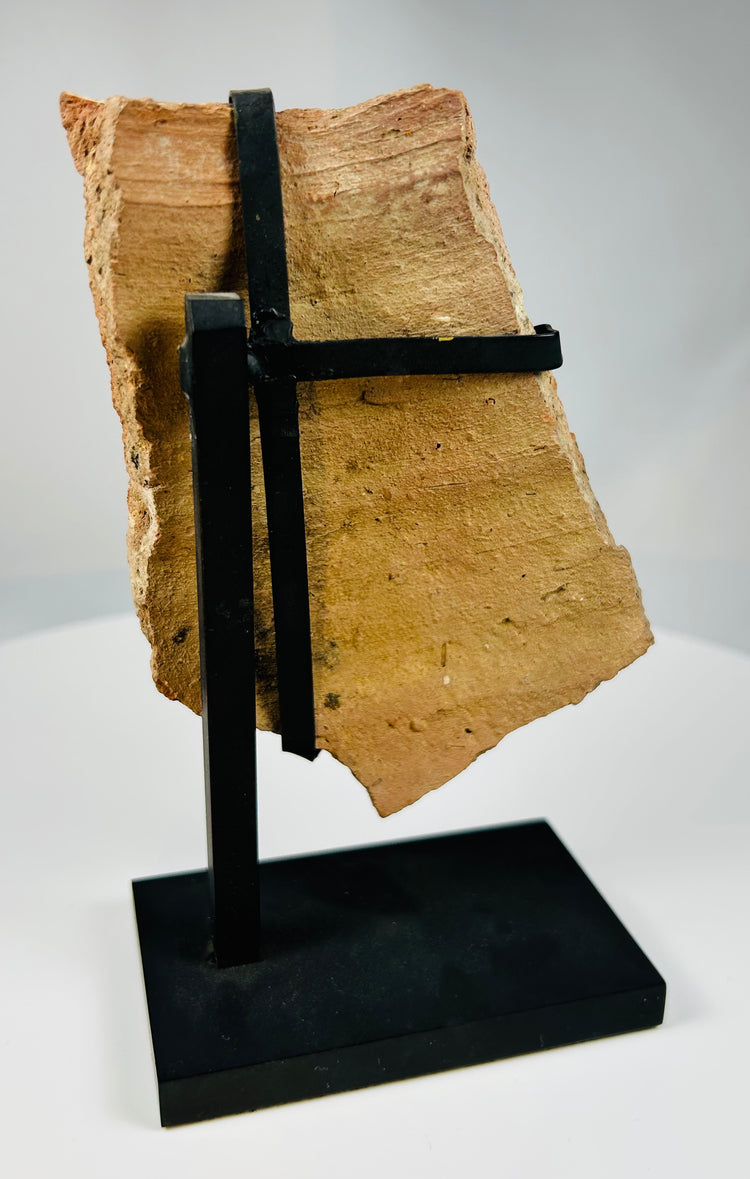 Ancient Greco-Roman terracotta mask fragment mounted for display, representing classical dramatic art.