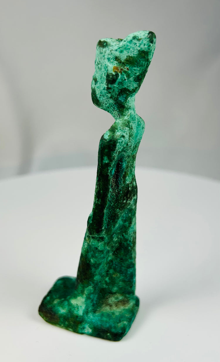 Ancient Egyptian bronze goddess figurine with stylized features and aged green patina.