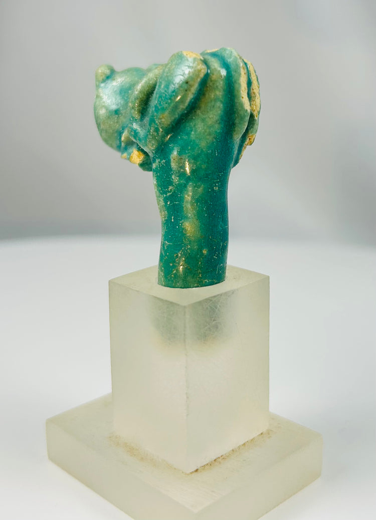 Ancient Egyptian faience cat head fragment symbolizing Bastet mounted on display stand.