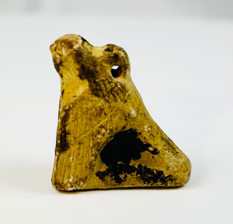 Small Egyptian falcon amulet carved in stone with natural mineral patina.