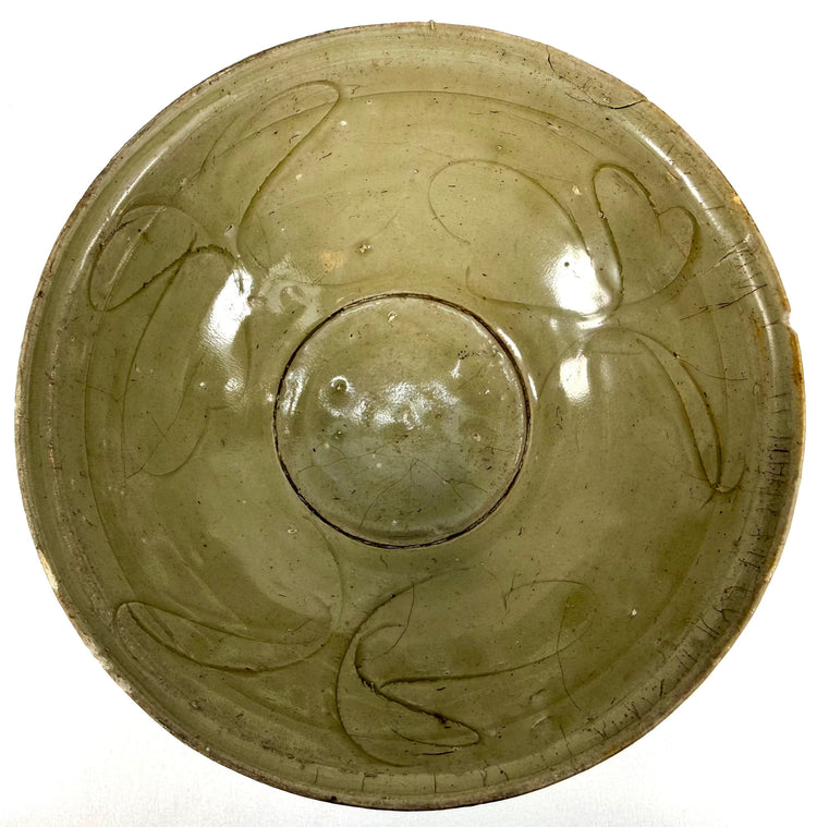 Twelfth-century Chinese ceramic bowl featuring an unglazed foot ring, exposed natural clay body, and subtle variations in celadon glaze coloration.