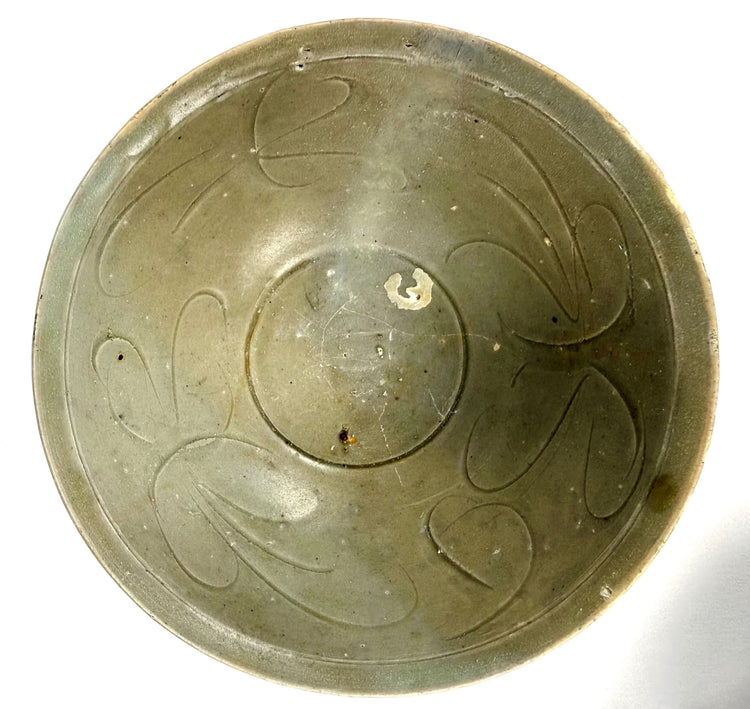 Ancient Chinese celadon-glazed bowl with a rounded body, gently flared rim, and decorative linear incisions along its exterior.