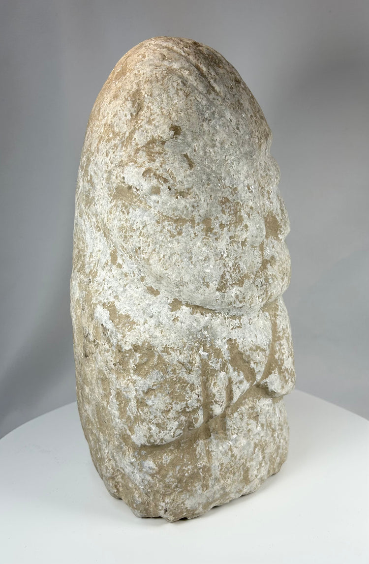 Ancient anthropomorphic stone carving with stylized proportions and aged texture