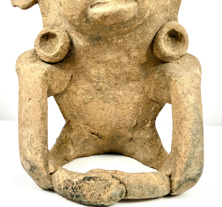 Ancient Mesoamerican terracotta figure with distinctive headpiece projections, sculpted facial details, and visible surface abrasions.