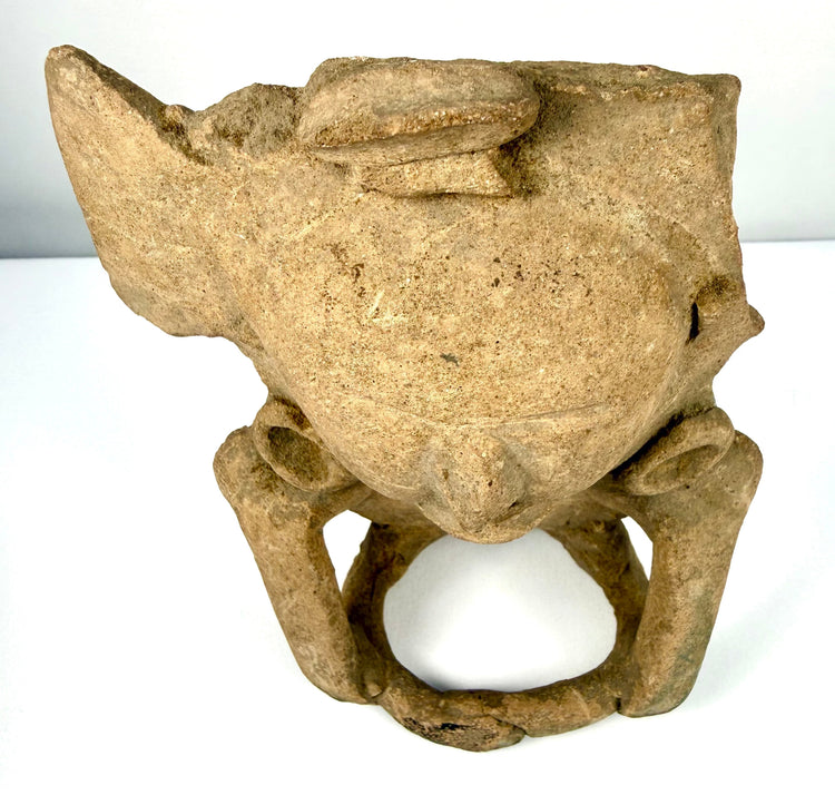Classic Period Pre-Columbian pottery figurine displaying a compact seated posture, elongated limbs, and darker areas of patination.