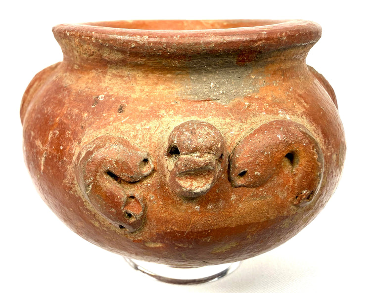 Pre-Columbian globular pottery vessel displaying applied decorative elements, curved relief motifs, and natural surface discoloration.