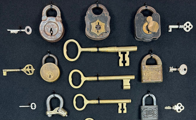 Historic lock collection with mixed metal padlocks and keys arranged in museum-style display frame
