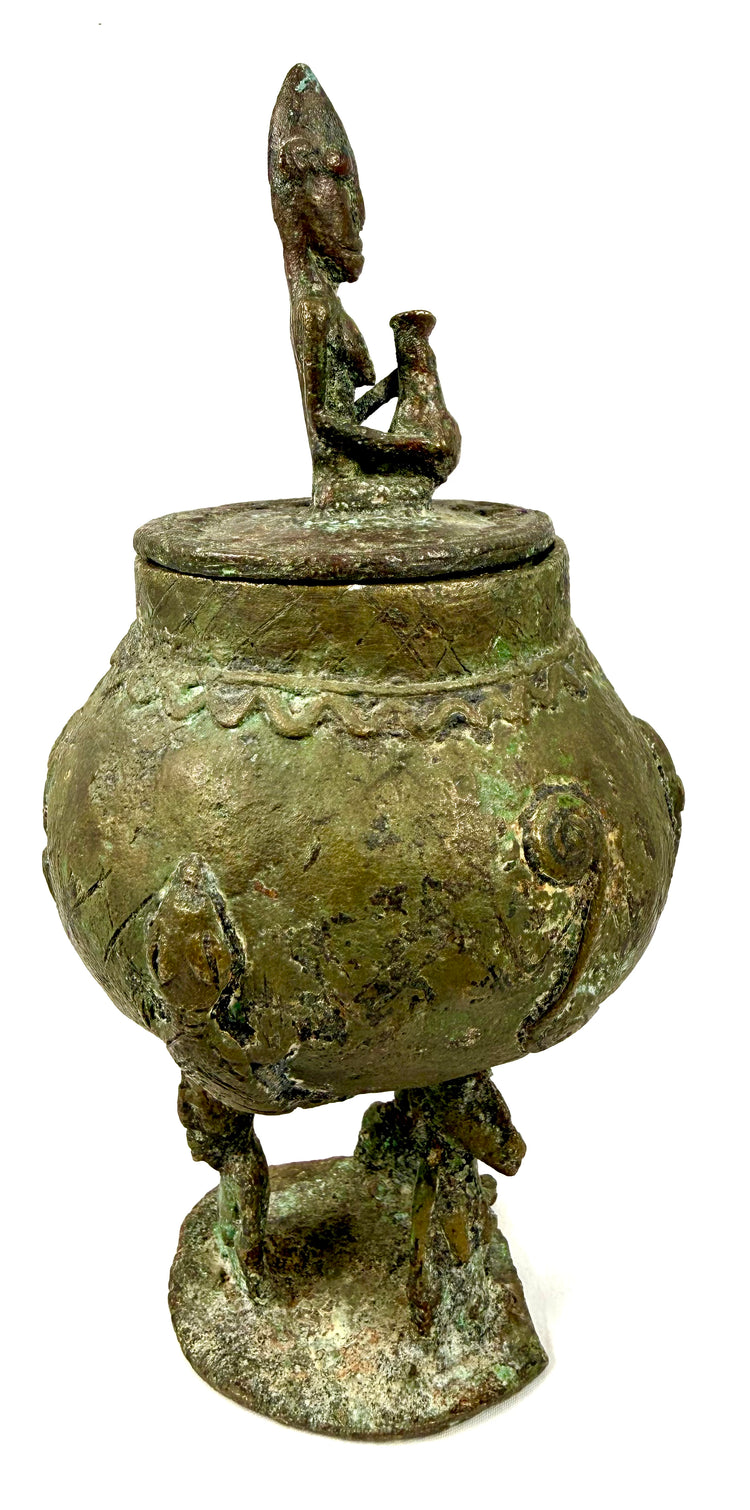 Dogon-attributed bronze container with a sculptural human finial and distinctive circular lid.