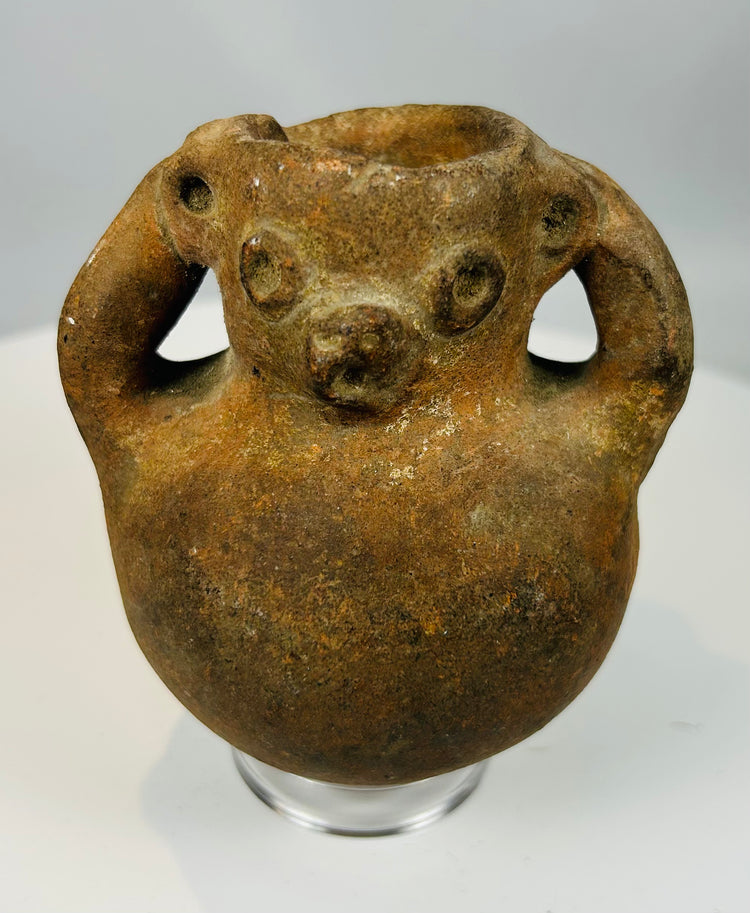 Pre-Columbian zoomorphic effigy vessel with sculpted face and dual loop handles showing heavy patina