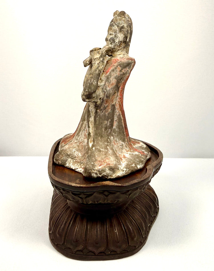 Chinese terracotta funerary sculpture depicting a seated female performer with flowing garments and a traditional pan flute.