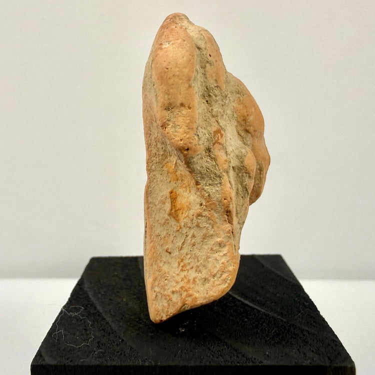 Side profile of rough textured terracotta artifact showing thickness and raised features