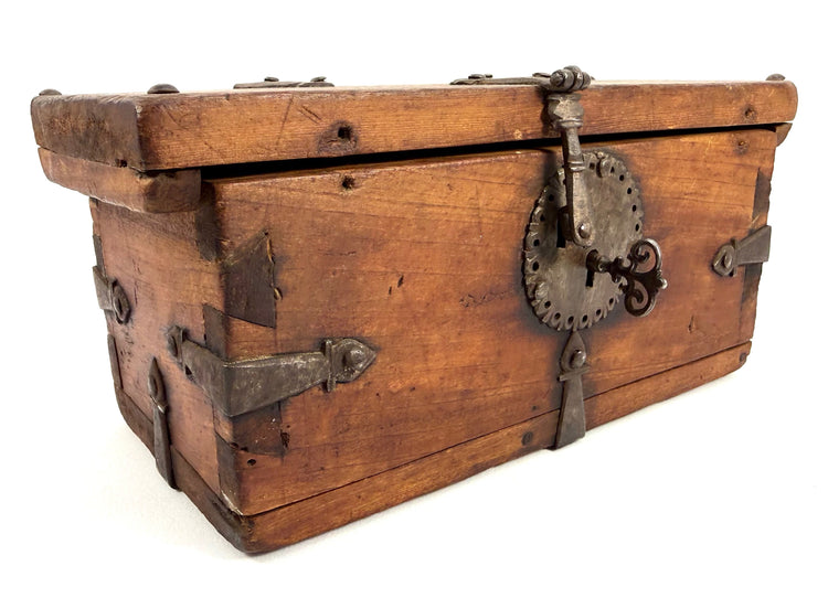 Frontal view of antique wooden strongbox with warm brown finish, iron corner straps, and large hasp plate