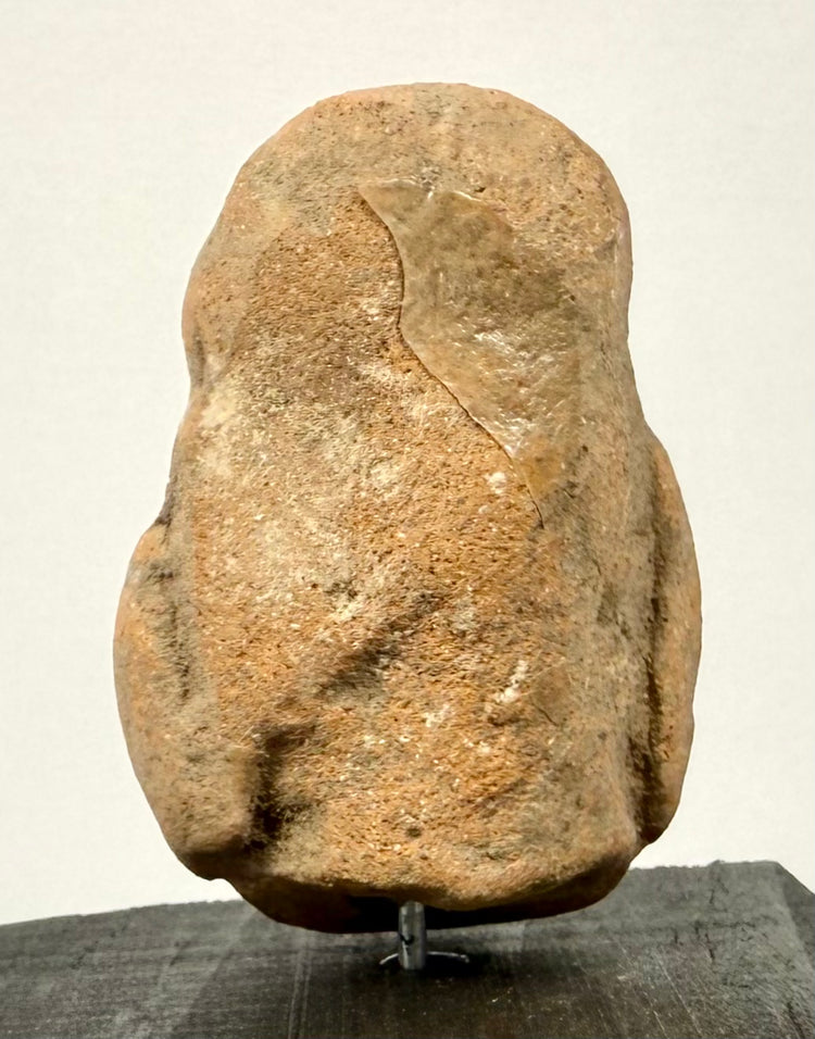 Rear view of ancient terracotta fragment with sandy texture and visible repair patch on upper back