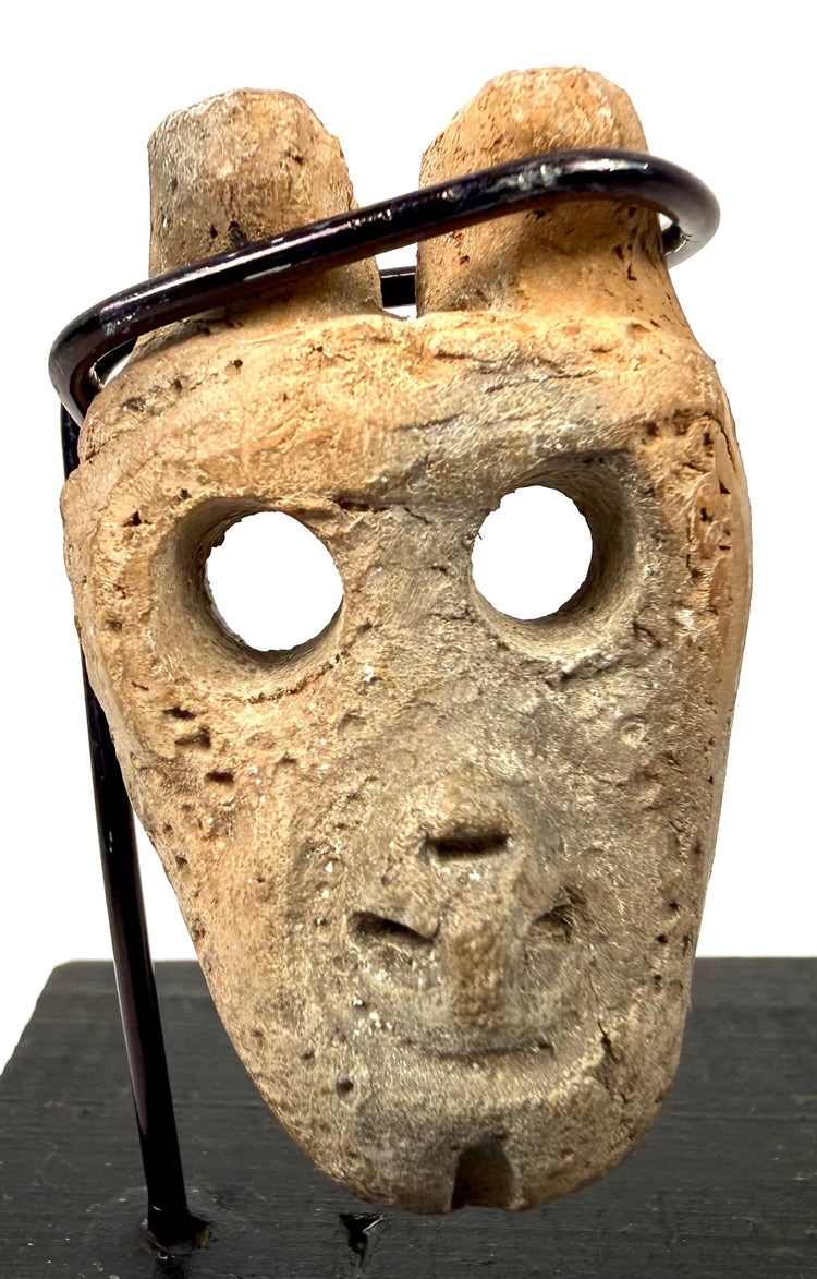 Ancient Mesoamerican anthropomorphic bone pendant featuring a stylized human face, recessed eyes, and twin suspension holes.