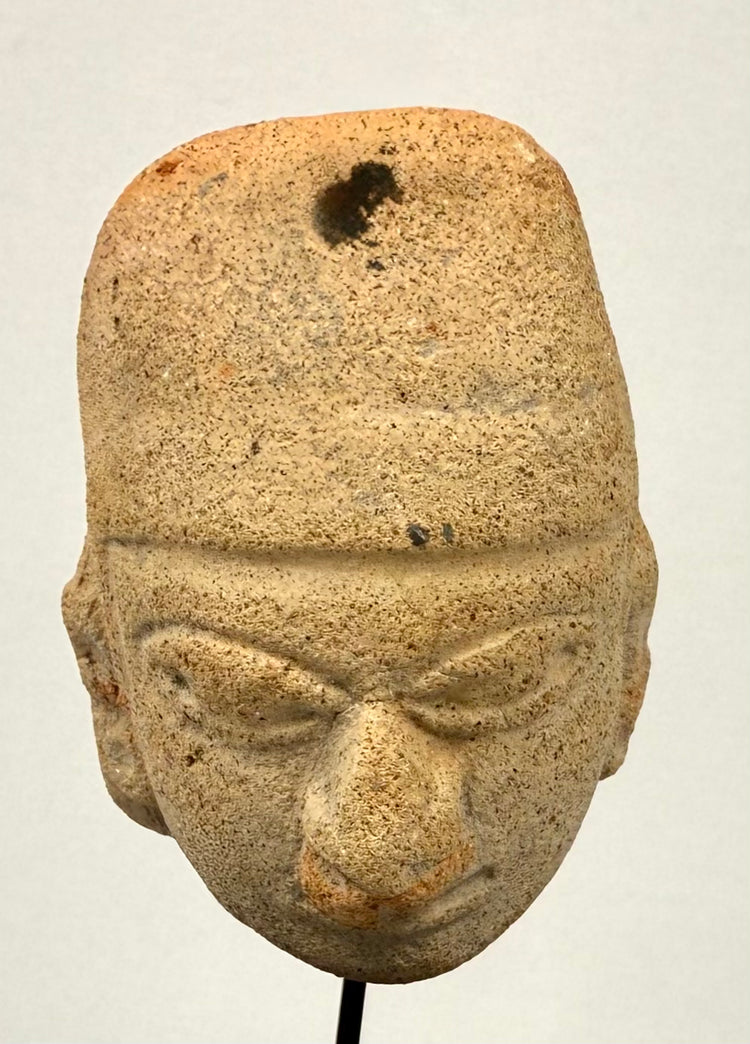 Macro detail of incised brow, heavy eyelids, and facial features on ancient clay face