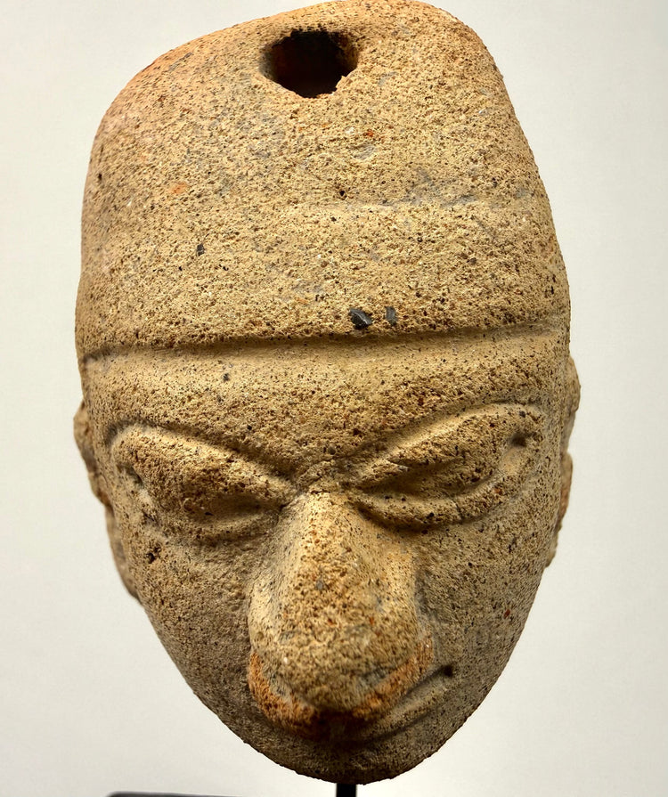 Frontal view of hand-modeled Mesoamerican clay pendant with distinct headdress line