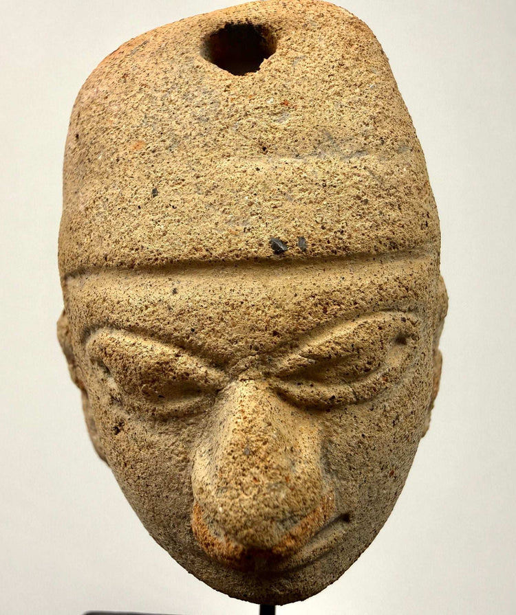 Frontal view of hand-modeled Mesoamerican clay pendant with distinct headdress line