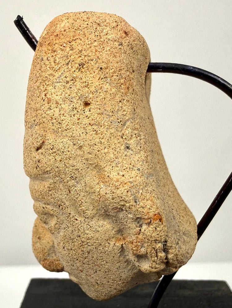 Side profile of weathered clay head sculpture showing porous texture and ear detail