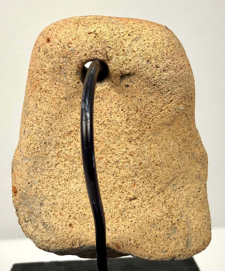Rear view of ancient clay pendant showing suspension hole and rough textured surface