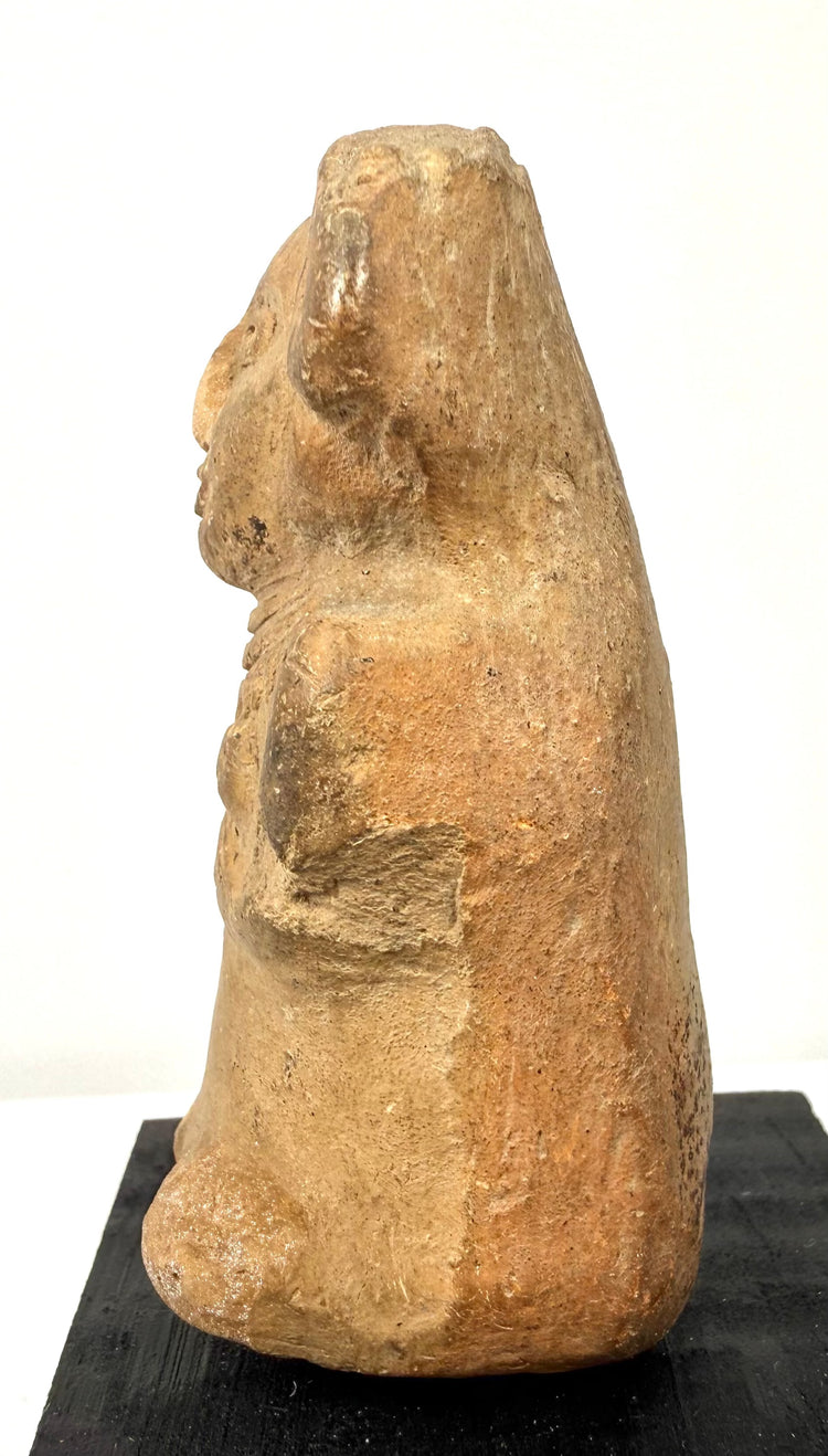 Left side view of beige ceramic ancient Mexican seated female figurine