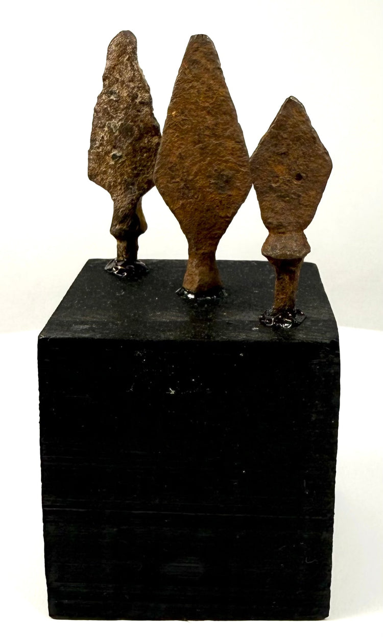 Three-piece mounted collection of ancient oxidized iron arrowheads on black pedestal